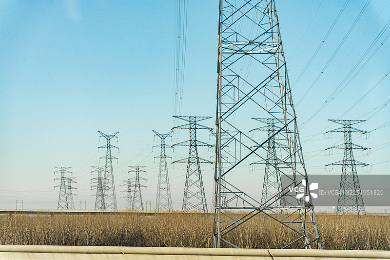 日落背景下的高压电塔，天空中的电力线条。图片素材