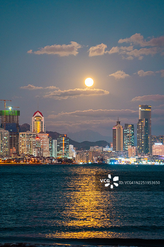 中国山东青岛第三海水浴场，傍晚时分，大都市的天际线灯火辉煌。图片素材