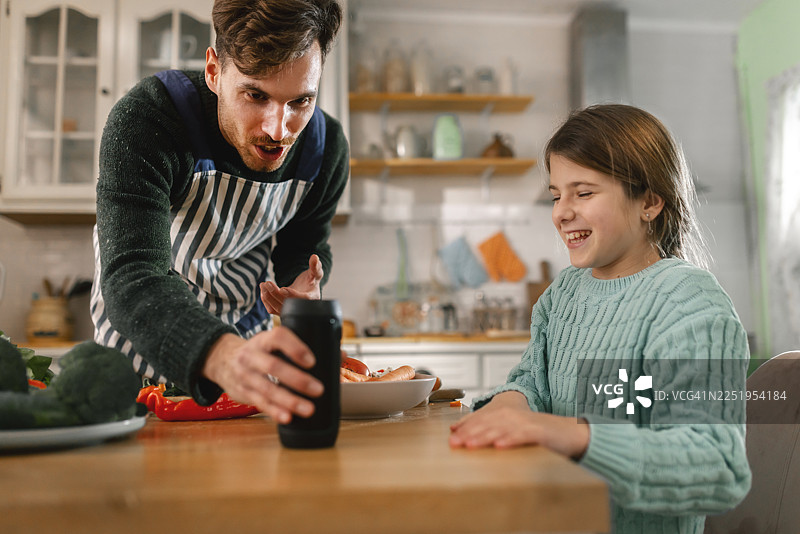 父亲和女儿在烹饪时，向智能语音助手询问食谱建议图片素材