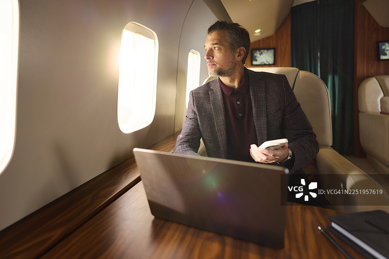 沉思的商人正在公司专机上使用无线技术。图片素材