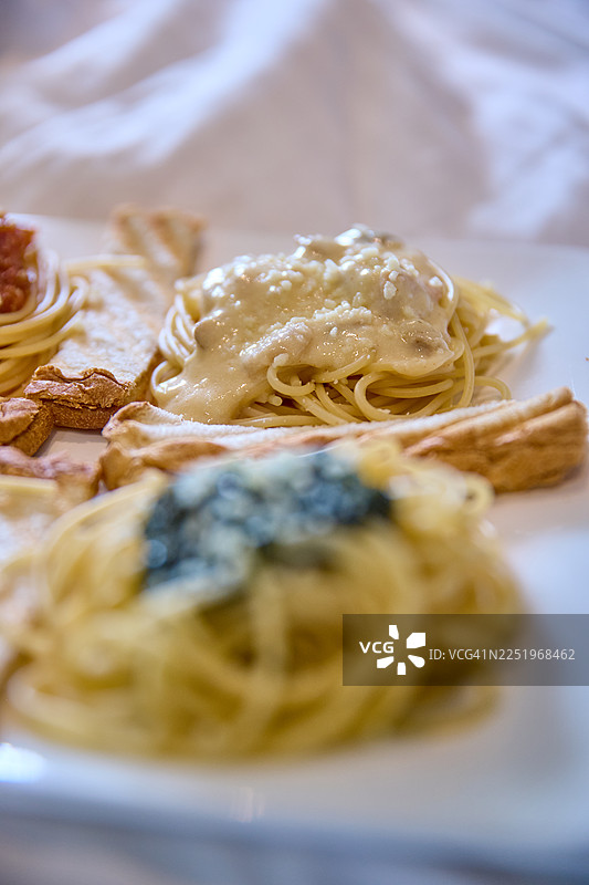 奶油白酱包裹着整齐卷起的意大利面，上面撒着细腻的奶酪碎。图片素材