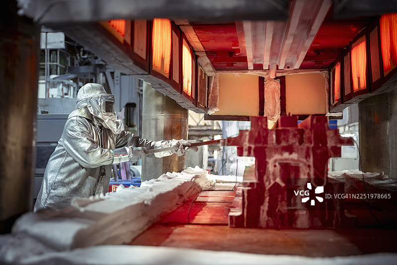 身穿隔热服的工程师在航空零部件工厂操作高温钛压机图片素材