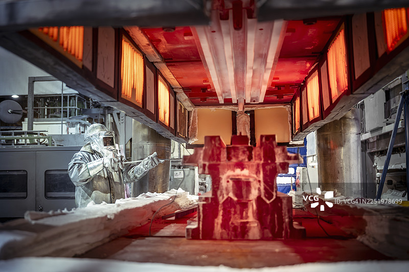 身穿隔热服的工程师正在航空零件工厂的高温压机中装载零件图片素材