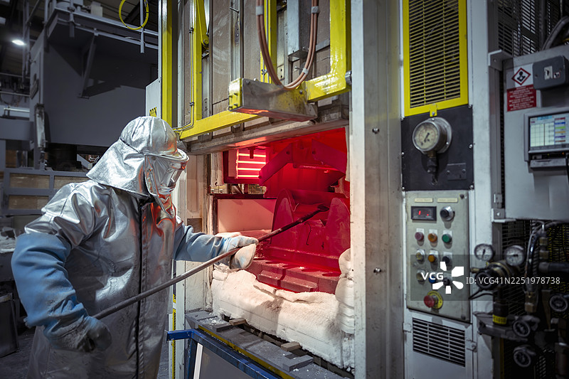身穿隔热服的工程师在航空零部件工厂操作高温钛压机图片素材