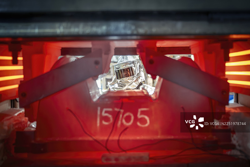 在航空航天零件工厂，透过高温钛压机看到的穿着隔热服的工程师图片素材