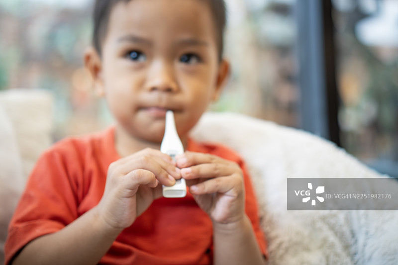 生病的小男孩，嘴里含着体温计图片素材