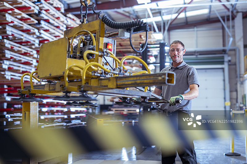 在航空航天零部件工厂的存储设施中，工程师正在操作真空吸盘吊具搬运金属板图片素材