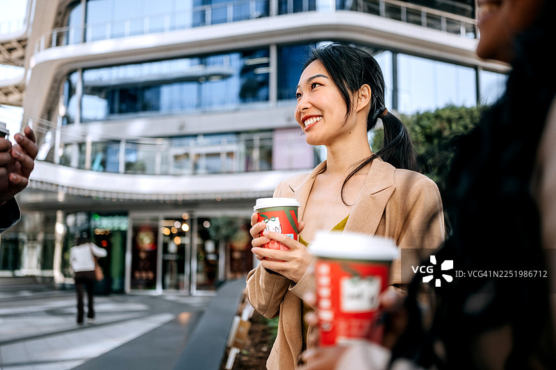 两位女商人正在户外边走边喝咖啡图片素材