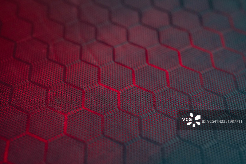 抽象蜂巢六边形塑料文件夹纹理，带有红色照明的微距背景图片素材