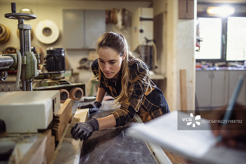 专注的中年白人女性在工作室使用刨木机图片素材