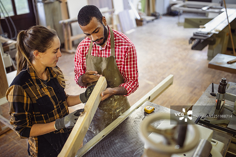 白人女性和男性同事正在评估木制手工艺品图片素材
