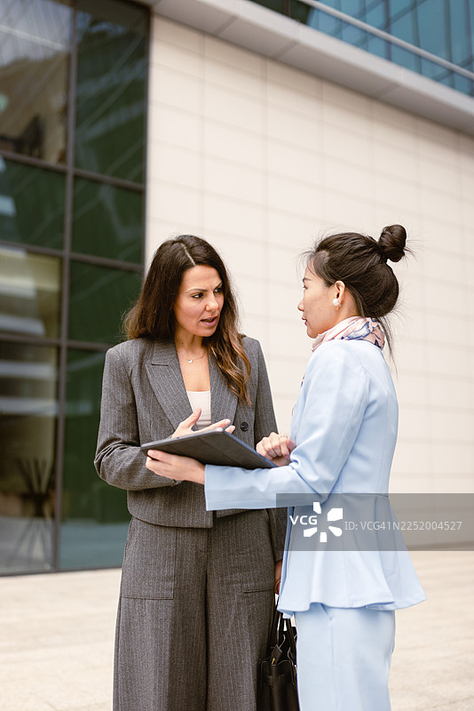 两位女商人正在现代办公楼外进行讨论图片素材
