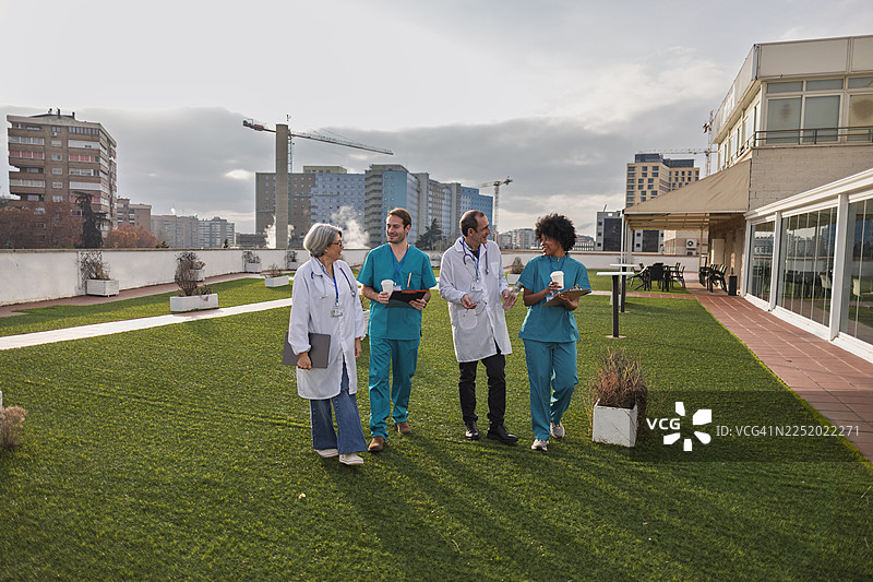 医疗团队在医院屋顶花园散步交谈图片素材