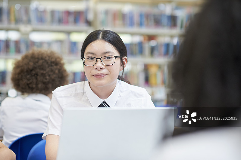 女学生在学校图书馆用笔记本电脑学习图片素材