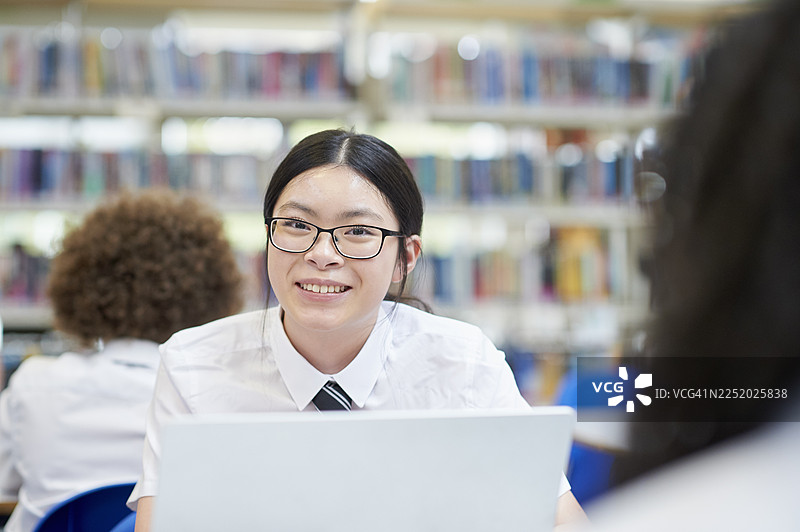 女学生在学校图书馆用笔记本电脑学习图片素材