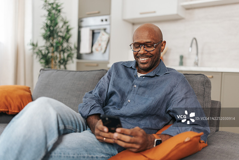 躺在沙发上笑着用手机的男人图片素材