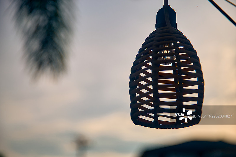 户外悬挂的编织吊灯灯罩的剪影。图片素材