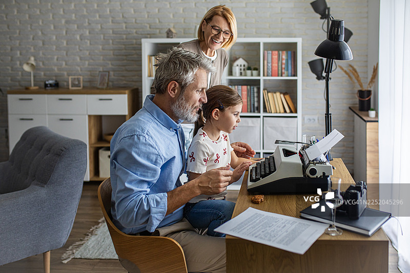 祖父母教孙女使用老式打字机图片素材