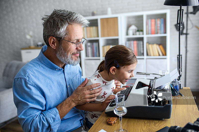祖父在老式打字机上教孙女打字图片素材