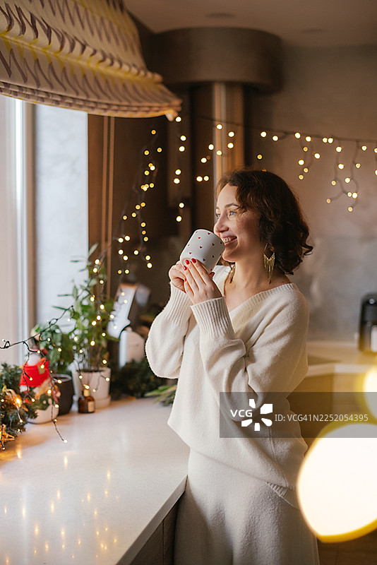 圣诞夜，一位女士在厨房里喝茶图片素材