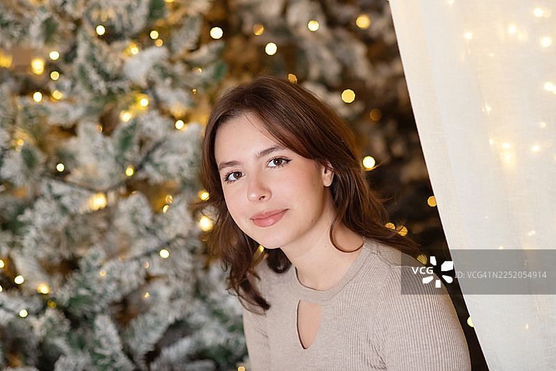 年轻女子在家庆祝圣诞节。家里装饰着圣诞灯，充满新年氛围。图片素材