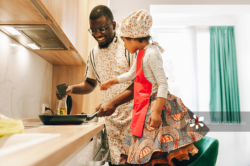 快乐的黑人父亲指导女儿制作可丽饼和煎饼的步骤图片素材
