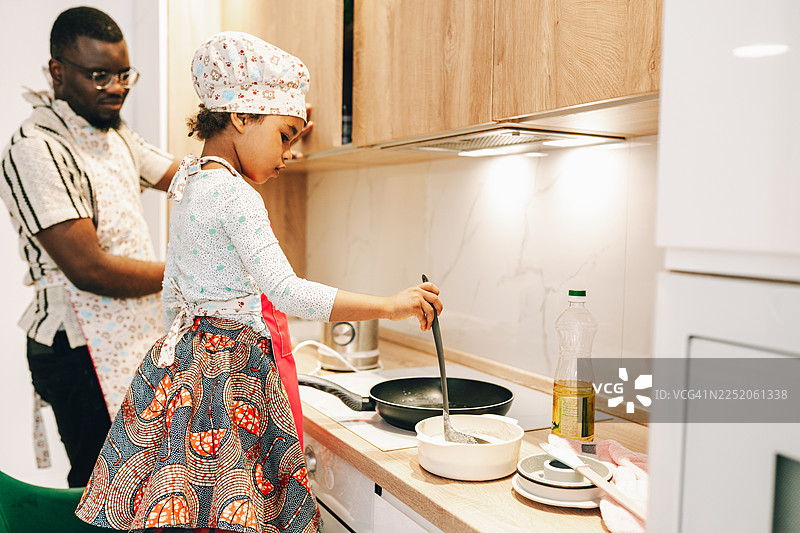 父女俩一起煎薄饼，爸爸指导小女儿烹饪薄饼图片素材