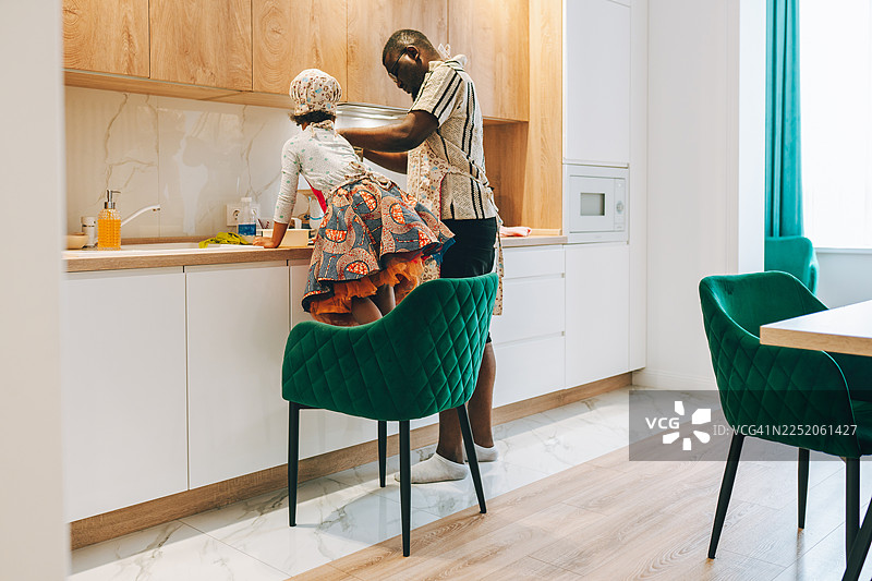 好奇的小女孩在厨房里帮助爸爸图片素材