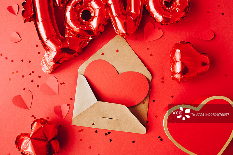浪漫的爱情信息概念，有信封和心形，周围环绕着红色装饰，非常适合情人节促销、婚礼请柬、订婚公告、生活方式博客和品牌故事。图片素材