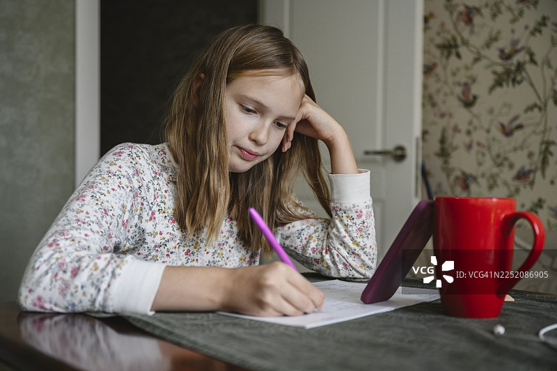 学生在家用手机和杯子写作业图片素材
