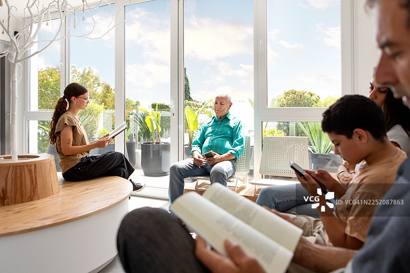 人们平静地坐在一间现代医疗诊所的候诊室里图片素材