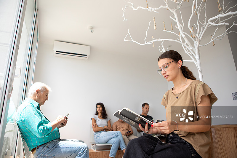 人们平静地坐着，身处一家现代医疗诊所的等候室图片素材