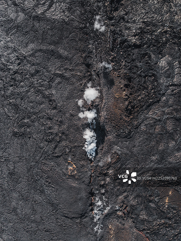 从冰岛雷克雅内斯半岛火山喷发后冷却的熔岩裂缝中升起的烟雾的俯视照片图片素材