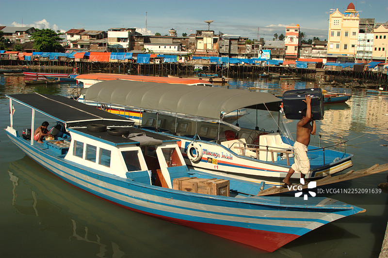一名印度尼西亚男子在印度尼西亚苏拉威西岛万鸦老港的船上取下行李箱图片素材