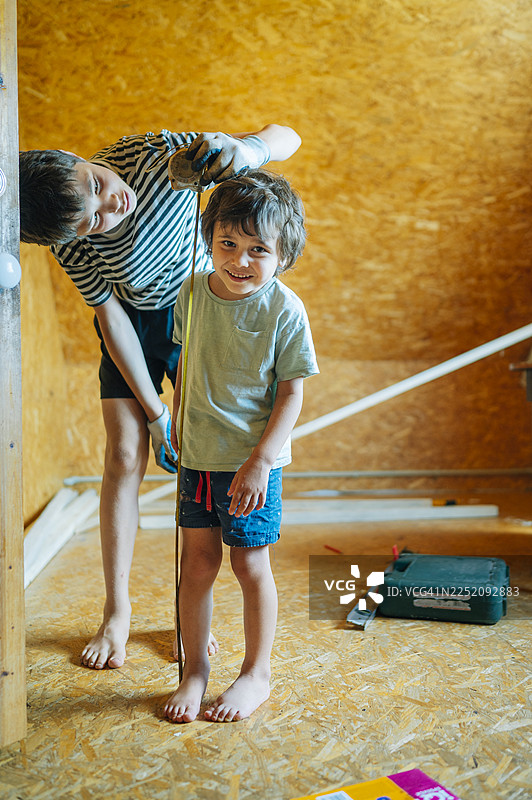 兄弟俩在室内进行房屋装修时互相测量图片素材