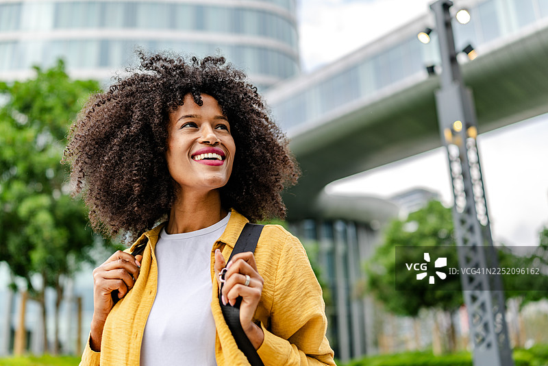 年轻的黑人女性在户外微笑，背景是建筑物图片素材