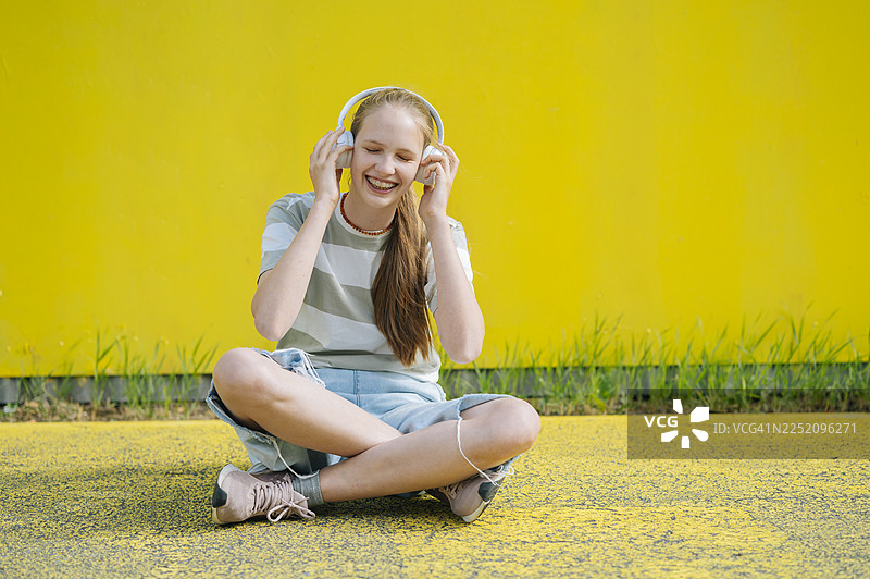 夏天户外戴着耳机听音乐的微笑的人图片素材