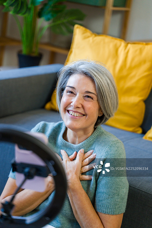 成熟的成年女性使用环形灯和手机进行视频博客录制图片素材