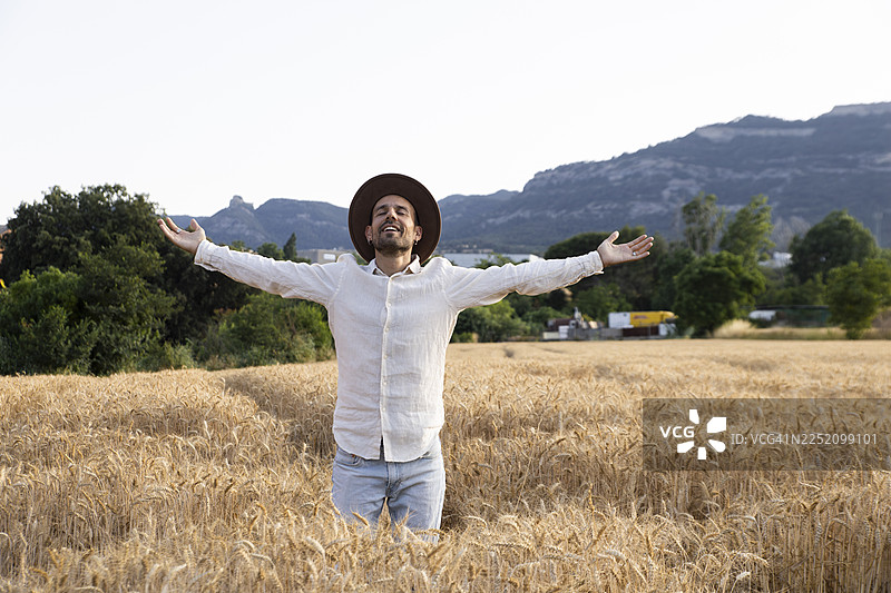 男人在户外的麦田里张开双臂表达感激之情图片素材
