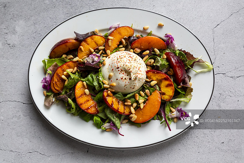 烤桃子和布拉塔奶酪沙拉，配以松子和可食用花卉图片素材