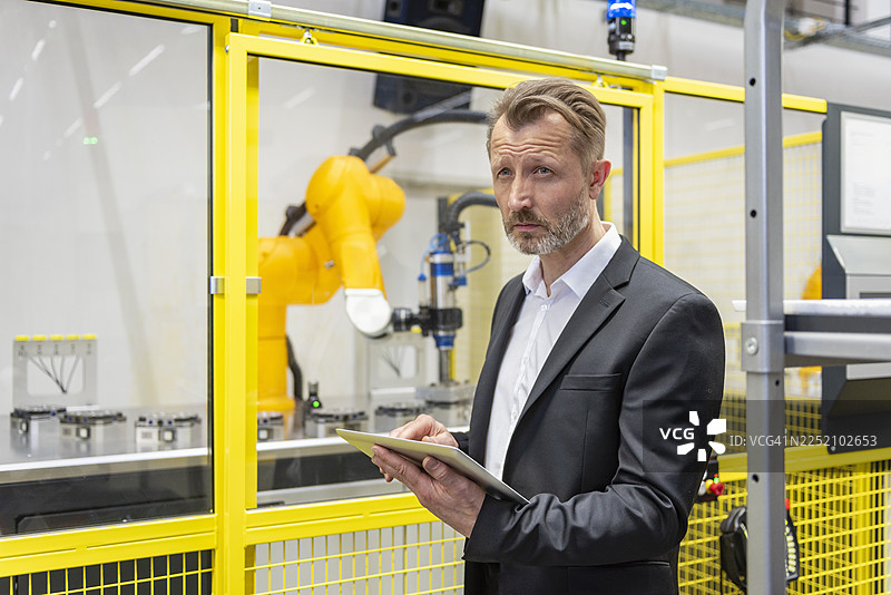 工程师在现代化工厂使用平板电脑与工业机器人互动图片素材