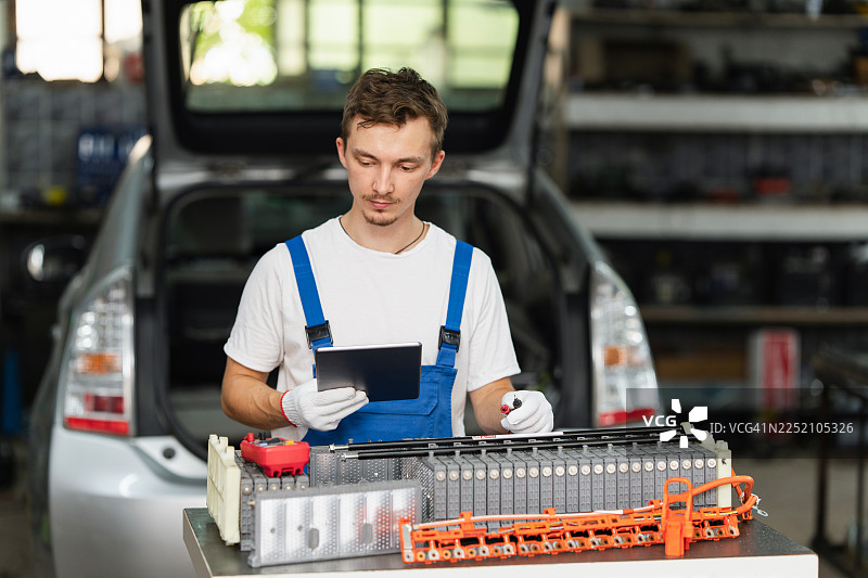 服务人员在车间使用数字平板电脑诊断电动汽车电池图片素材