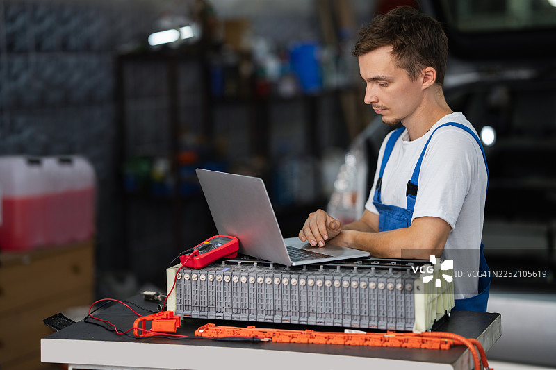 服务人员在车间使用笔记本电脑诊断电动汽车电池组图片素材