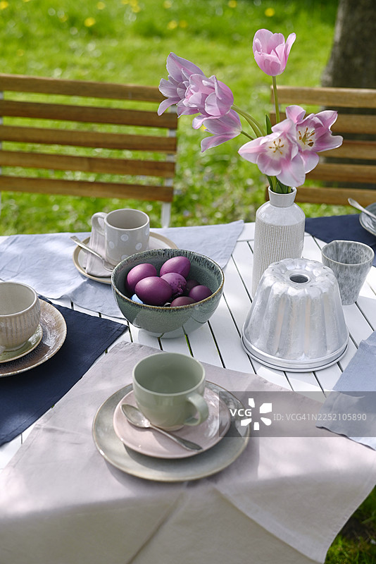 花园户外复活节餐桌，摆放着郁金香和紫罗兰色彩的彩蛋图片素材