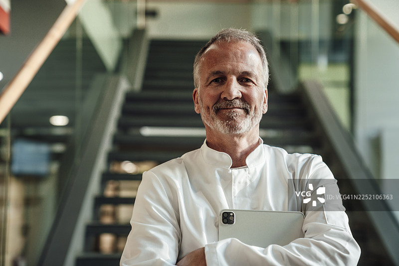 身穿白大褂的医生手持平板电脑站在现代诊所里图片素材