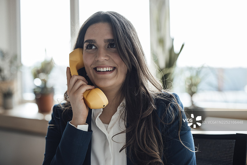 身着正装的女商人在办公室里微笑着接听电话图片素材