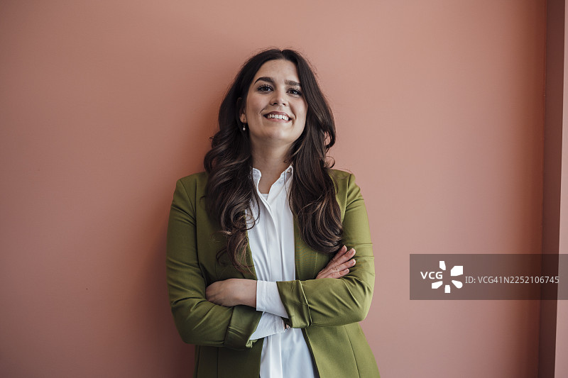 自信的女商人在办公室里穿着绿色西装外套，面带微笑图片素材