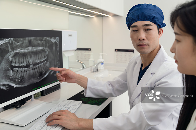 牙医在牙科诊所办公室与患者讨论计划的牙齿治疗。图片素材