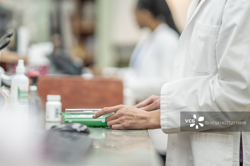 身穿白大褂的实验室技术人员在临床实验室中处理医疗托盘和瓶子图片素材