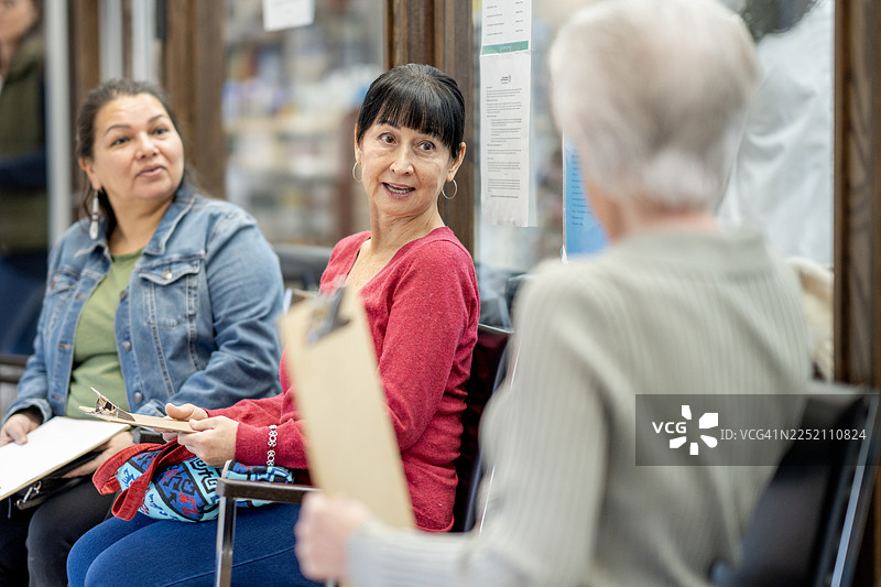 一群不同背景的女性坐在诊所等候区愉快地交谈图片素材
